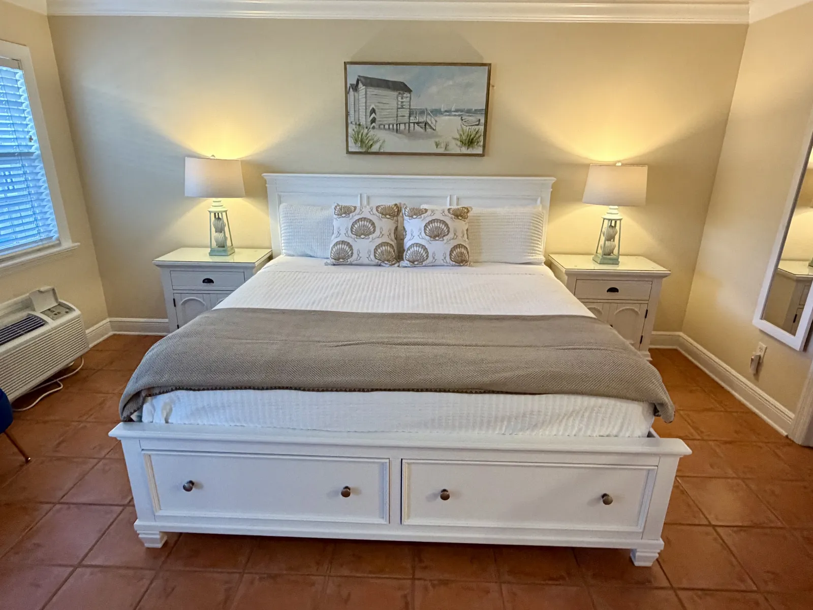 Full view king size bed with tan throw blanket and pillows with designs
