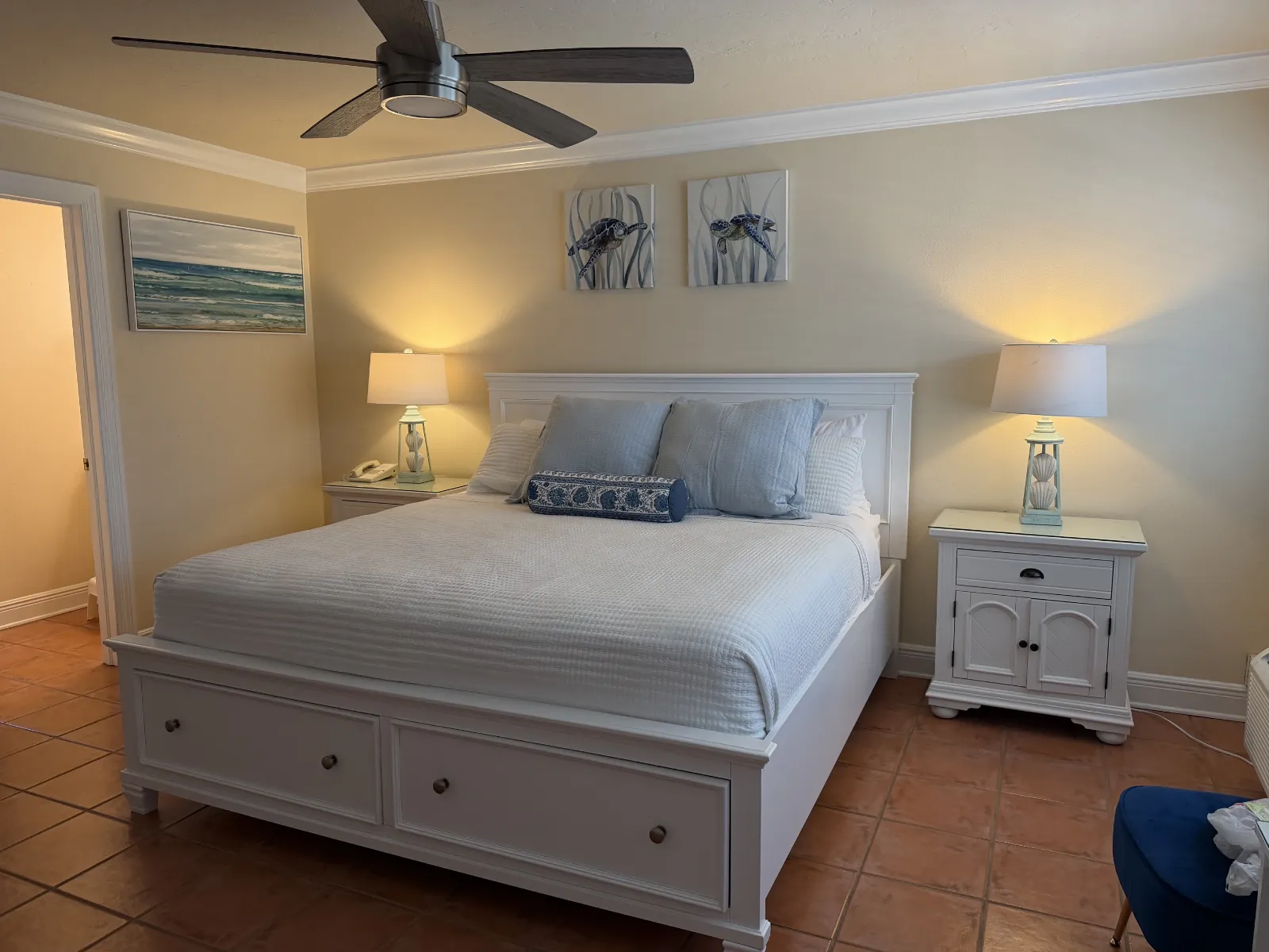 Full view with ceiling fan light blue pillows and pictures on the wall