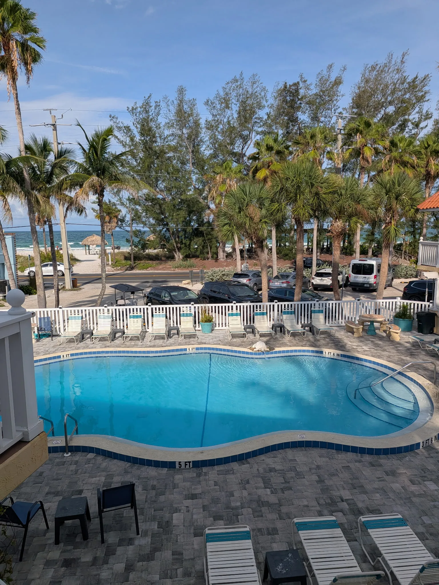 Heated outdoor resort swimming pool surrounded by paved sun deck and tropical palm trees